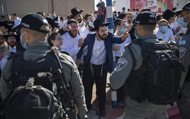 Ultra-Orthodox Jews argue with Israeli border police officers during a protest over the coronavirus lockdown restrictions, in Ashdod, Israel, Sunday, Jan. 24, 2021. As he seeks re-election, Prime Minister Benjamin Netanyahu has turned to a straightforward strategy: Count on the rock-solid support of his ultra-Orthodox political allies and stamp out the coronavirus pandemic with one of the world’s most aggressive vaccination campaigns. But with ultra-Orthodox communities openly flouting safety guidelines and violently clashing with police trying to enforce them, this marriage of convenience is turning into a burden. (AP Photo/Oded Balilty)