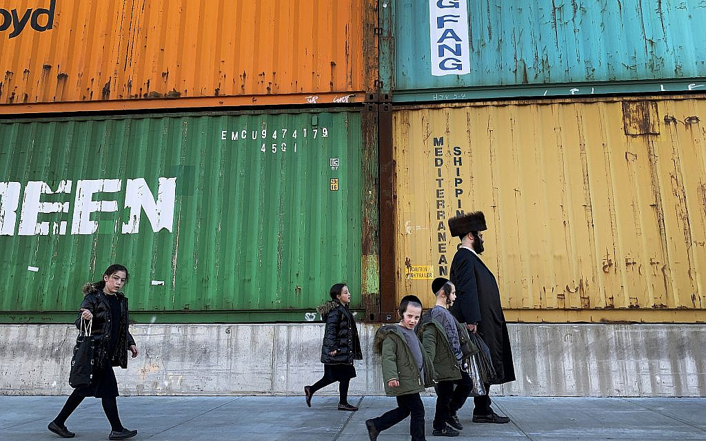 In this Tuesday, March 30, 2021 file photo, members of the Orthodox Jewish community walk past shipping containers in the South Williamsburg neighborhood of Brooklyn, New York. (AP Photo/Wong Maye-E)