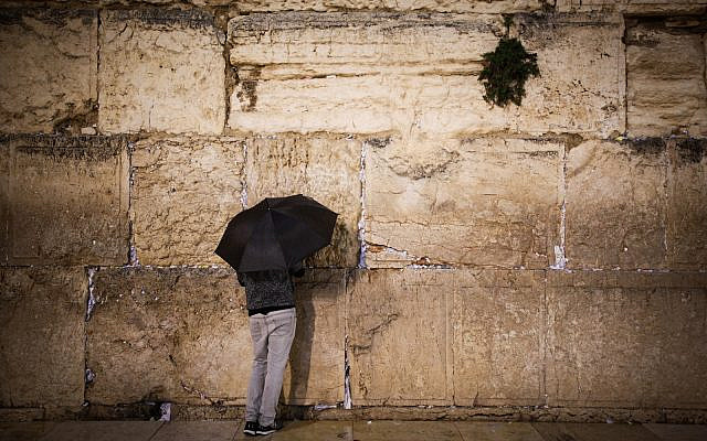 A man holds umbrella to protect himself from the rain, at the Western Wall in Jerusalem's Old City on December 20, 2018. (Aharon Krohn/Flash90)