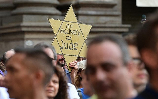 A protester holds a Yellow Star reading "Not Vaccinated = Jew." (Photo by MIGUEL MEDINA / AFP)