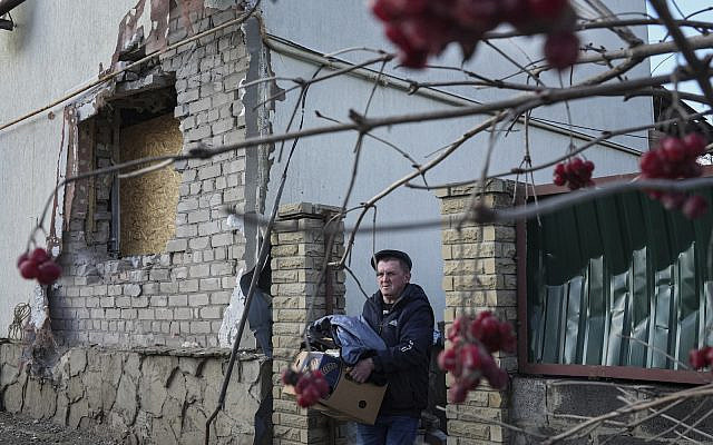 A man takes items out of his house after it was damaged by artillery shelling in Novoluhanske, eastern Ukraine, Wednesday, Feb. 23, 2022. (AP Photo/Evgeniy Maloletka)