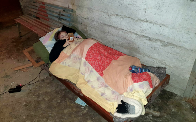 Yuliya Matyushenko, a 19-year-old with SMA type 2, reads news on her cellphone while resting in a makeshift underground shelter as her city, Kharkiv, is bombed by Russian forces. (Vitaliy Matyushenko)