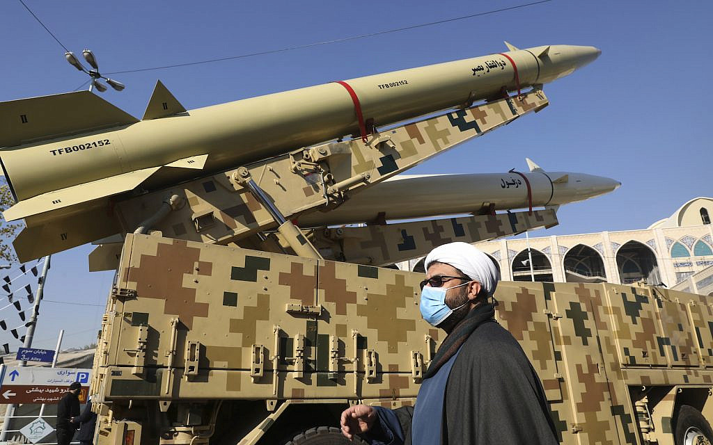 A cleric walks past Zolfaghar, top, and Dezful missiles displayed in a missile capabilities exhibition by the paramilitary Revolutionary Guard a day prior to the second anniversary of Iran's missile strike on US bases in Iraq in retaliation for the US drone strike that killed top Iranian general Qassem Soleimani in Baghdad, at Imam Khomeini grand mosque, in Tehran, Iran, Friday, Jan. 7, 2022. (AP Photo/Vahid Salemi)