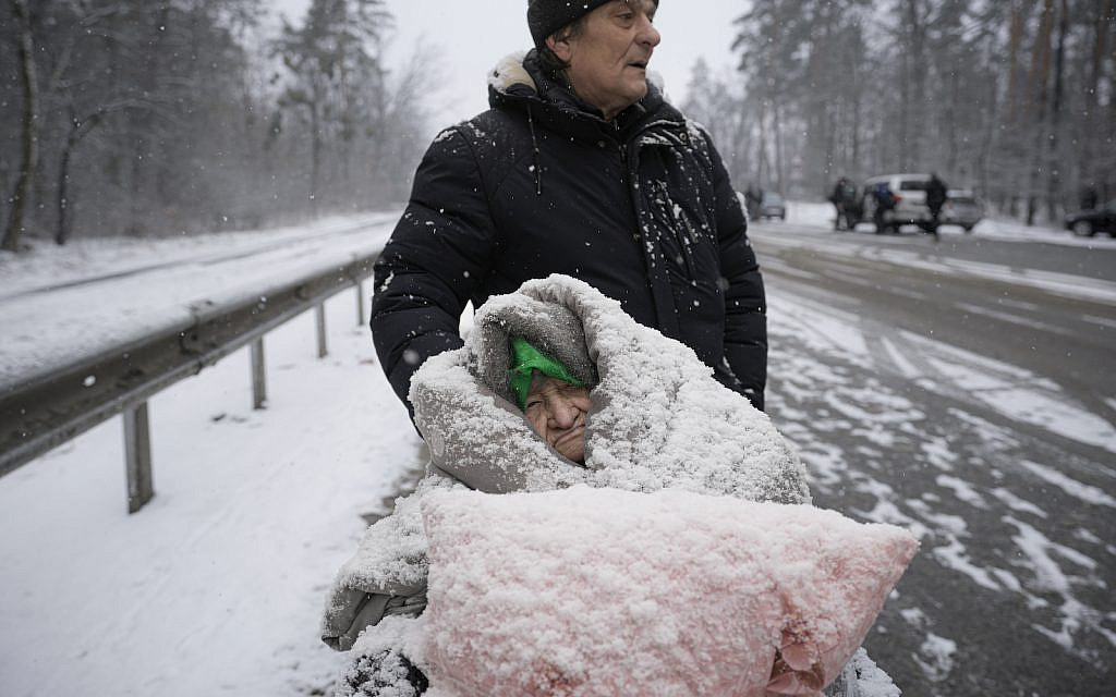 An elderly woman is coated in snow as she sits in a wheelchair after being evacuated from Irpin, on the outskirts of Kyiv, Ukraine, Tuesday, March 8, 2022. (AP Photo/Vadim Ghirda)