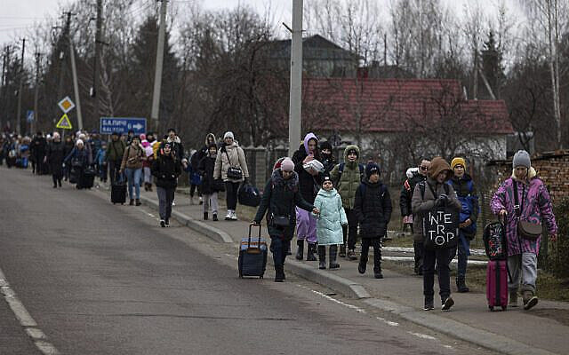 Groups of Ukrainian refugees walk along the road between Lviv and Shehyni, in Volytsya, Ukraine, Saturday March 5, 2022. The number of Ukrainians forced from their country since the Russian invasion has been increasing on a daily basis. (AP Photo/Marc Sanye)