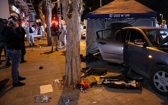Israeli security forces near a car suspected to have been used by two terrorists who carried out a deadly attack in Hadera on March 27, 2022. (GIL COHEN-MAGEN / AFP)