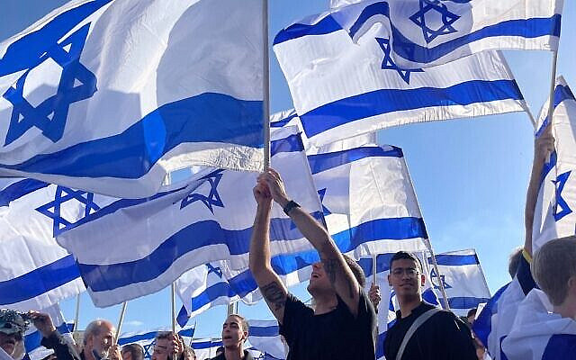 Illustrative: Israelis wave flags outside Jerusalem's Old City on April 20, 2022. (Carrie Keller-Lynn/Times of Israel)