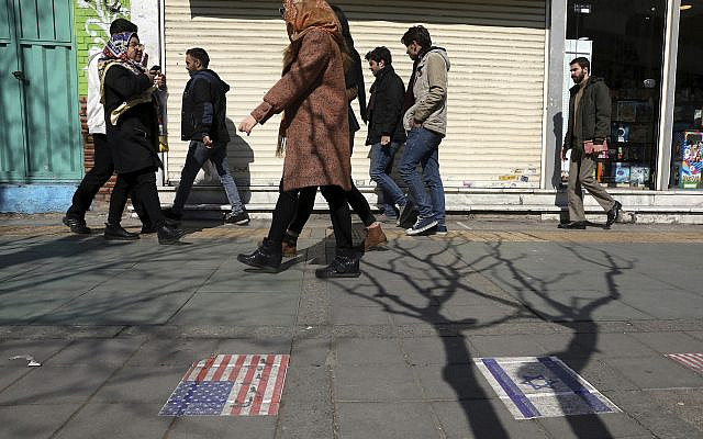 Pedestrians walk past representations of the US and Israeli flags pasted on the ground on Enqelab-e-Eslami (Islamic Revolution) street in downtown Tehran, Iran, Thursday, Feb. 13, 2020. (AP Photo/Vahid Salemi)