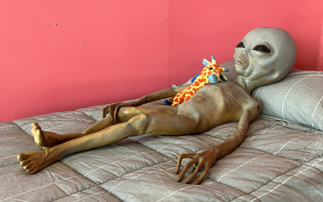 An alien lounges on a bedspread as part of a window-display gimmick at White Mattress fronting Main Street in Roswell, New Mexico. (Photo by Larry Luxner)