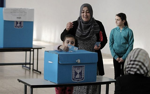 An Arab Israeli girl casts her mother's ballot at a polling station in the northern Israeli town of Umm al-Fahm on March 17, 2015. (AFP/Ahmad Gharabli/File)