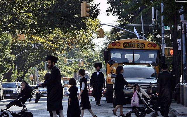 In this Sept. 20, 2013 file photo, children and adults cross a street in front of a school bus in Borough Park, a neighborhood in the Brooklyn borough of New York that is home to many ultra-Orthodox Jewish families. Critics have charged for years that the rudimentary level of secular education at private yeshiva schools serving New York's Hasidic communities are deficient in teaching science, geography and math to grade school students. Now, for the first time, the city Department of Education is investigating more than three dozen of the schools to make sure their instruction is up to the most basic standards. (AP Photo/Bebeto Matthews, File)