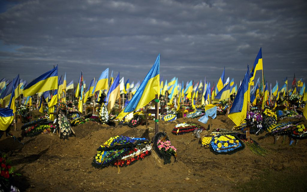 Ukrainian flags wave next to graves of recently killed Ukrainian servicemen in a cemetery during Ukraine Defenders Day in Kharkiv, Ukraine, Friday, Oct. 14, 2022. (AP Photo/Francisco Seco)