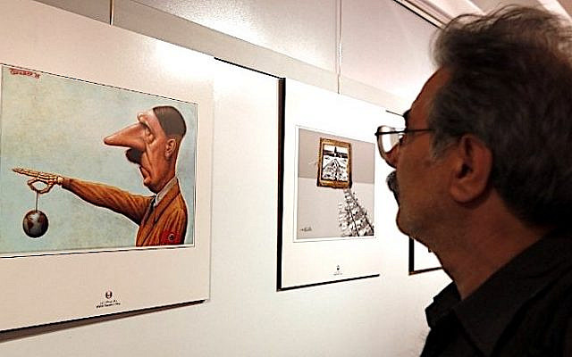 An Iranian man looks at a cartoon showing Adolf Hilter at the second international exhibition of drawing and cartoons on the Holocaust in Tehran on May 14, 2016. The third such contest was held in 2020. (AFP / ATTA KENARE)