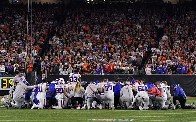 Buffalo Bills players huddle and pray after teammate Damar Hamlin collapsed on the field after making a tackle against the Cincinnati Bengals during the first quarter at Paycor Stadium on January 2, 2023, in Cincinnati, Ohio. (Dylan Buell/Getty Images/AFP)