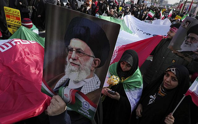 Participants in the annual rally commemorating Iran's 1979 Islamic Revolution carry a huge Iranian flag and posters of the Supreme Leader Ayatollah Ali Khamenei, in Tehran, Feb. 11, 2023. (AP Photo/Vahid Salemi)