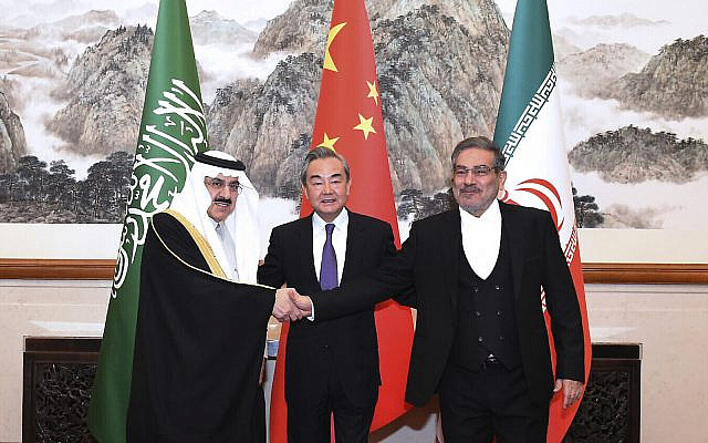 In this photo released by Xinhua News Agency, Ali Shamkhani, the secretary of Iran's Supreme National Security Council, at right, shakes hands with Saudi national security adviser Musaad bin Mohammed al-Aiban, at left, as Wang Yi, China's most senior diplomat, looks on, at center, for a photo during a closed meeting held in Beijing, March 11, 2023. (Luo Xiaoguang/Xinhua via AP)