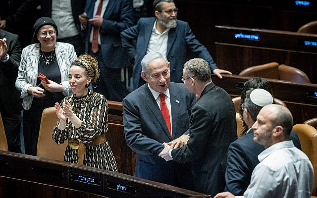 Prime Minister Benjamin Netanyahu, Justice Minister Yariv Levin and coalition members celebrate after a vote on the government's judicial overhaul plans in the Knesset, February 21, 2023 (Yonatan Sindel/Flash90)