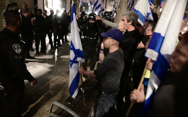 Police officers stand guard while Israelis demonstrate against the Prime Minister's wife Sara Netanyahu, outside a hair salon in Tel Aviv.