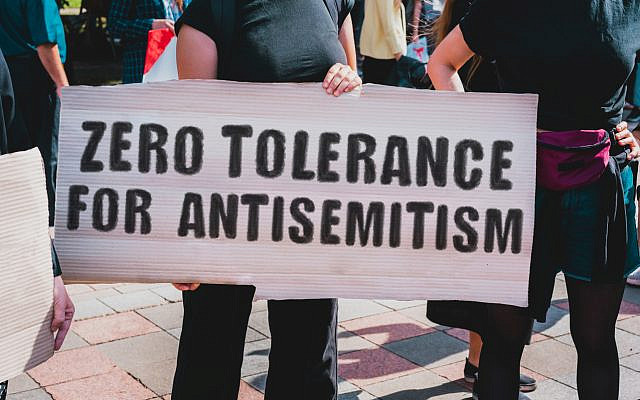 The phrase " Zero tolerance for antisemitism " drawn on a carton banner in hand. A girl holds a cardboard with an inscription during a march.