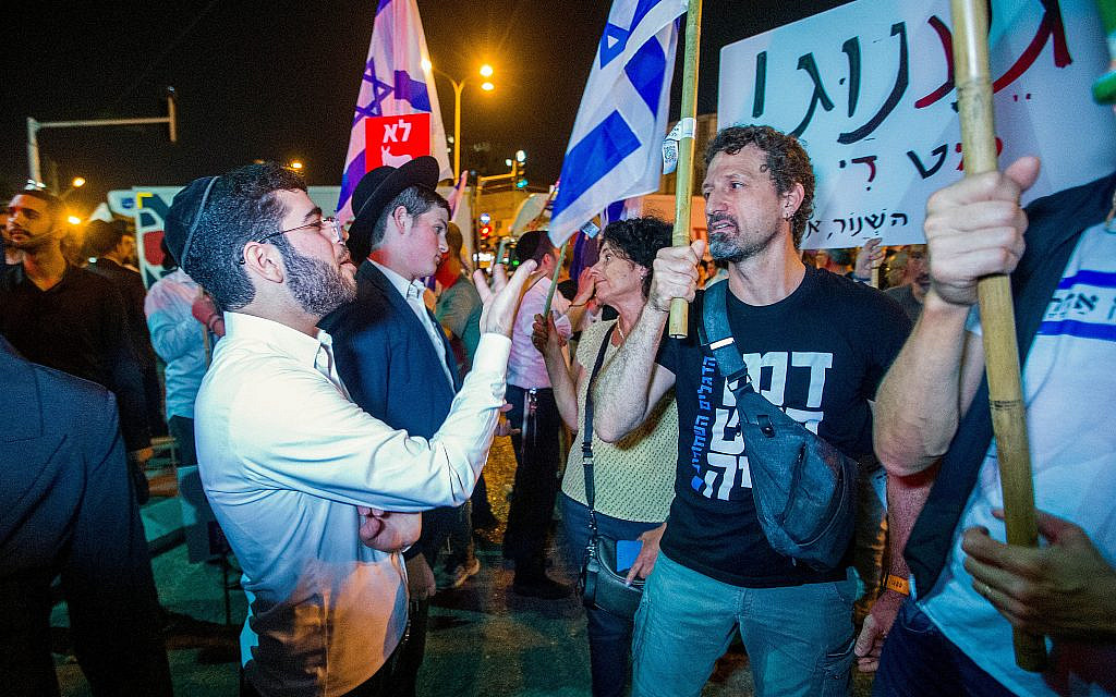 Demonstrators argue with ultra-Orthodox Jews during a protest march in Bnei Brak against funding to ultra-Orthodox parties in the state budget, on May 17, 2023. (Flash90)