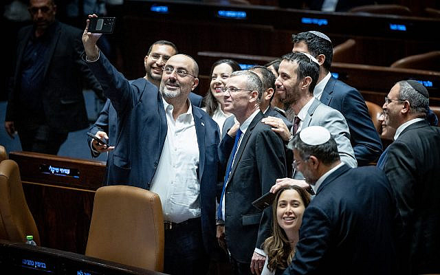 Coalition lawmakers crowd around Justice Minister Yariv Levin to take a celebratory selfie in the Knesset plenum, as they pass the first of the coalition's judicial overhaul laws, July 24, 2023. (Yonatan Sindel/ Flash90)