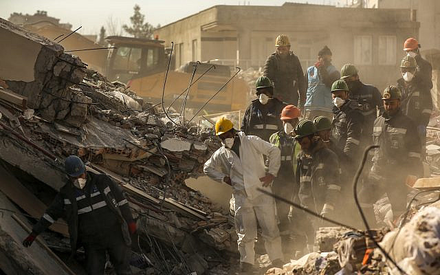 Rescue workers stand on a collapsed building in Adiyaman, southern Turkey, February 11, 2023. (AP Photo/Emrah Gurel)