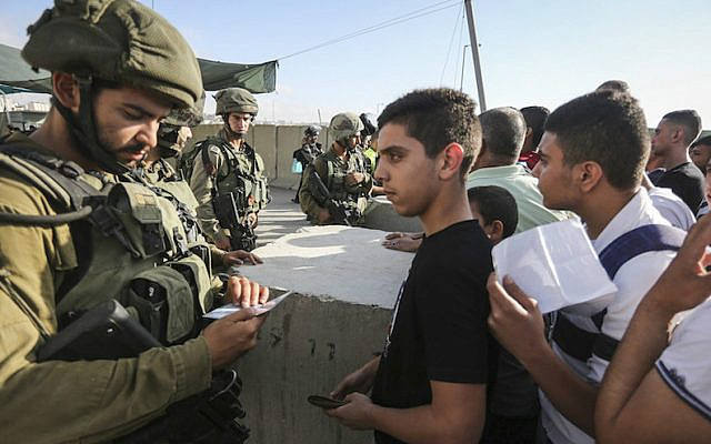 Israeli soldiers checking Palestinian IDs at the Qalandia checkpoint between the West Bank city of Ramallah and Jerusalem, July 1, 2016. (Flash90)