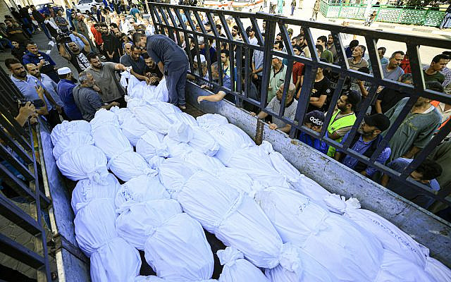 A truck carries bodies wrapped in burial shrouds of the Abu al-Awf family and other victims, displaced from northern Gaza and killed in a home housing internally displaced Palestinians, as they are taken for burial from the Al-Aqsa hospital in the town of Deir Al-Balah, in the central Gaza Strip, on October 15, 2023 (Mahmud HAMS / AFP)