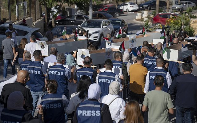 Palestinian journalists carry mock coffins of Palestinian journalists who were killed during the current war in Gaza during a symbolic funeral toward a United Nations office, in the West Bank city of Ramallah, Tuesday, Nov. 7, 2023. (AP Photo/Nasser Nasser)