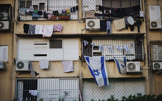 Israeli flags hang outside an apartment of a Jewish family at a building where Arab families also live in the Ramat Eshkol neighborhood in the mixed Arab-Jewish town of Lod, central Israel, May 28, 2021. (AP Photo/David Goldman/File)