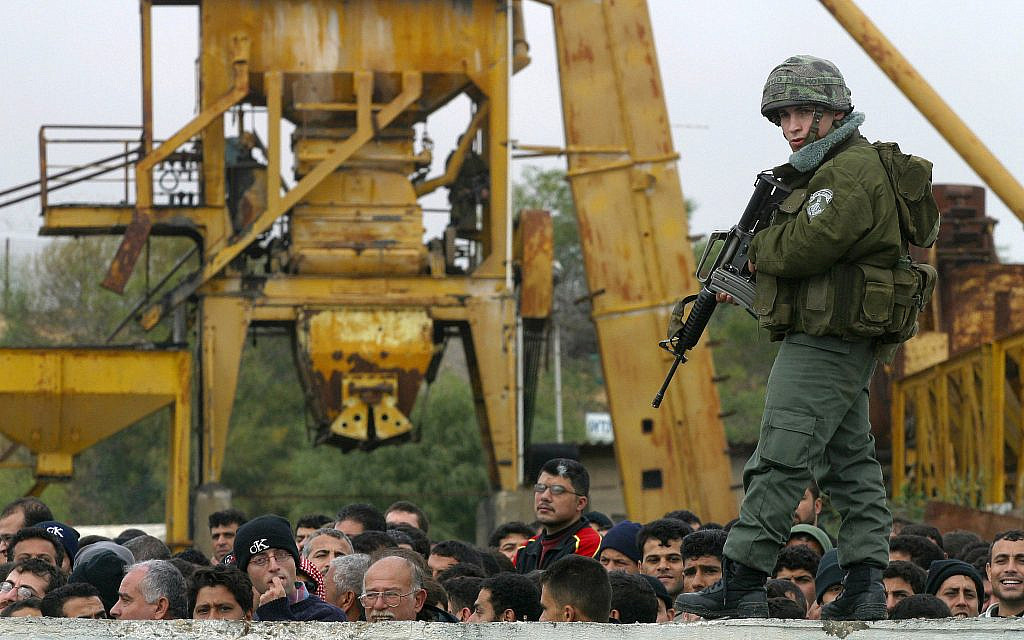 In this 2004 file photo, an IDF soldier guards Palestinian workers at the Erez border checkpoint in Gaza following an attack by female suicide bomber. April 18, 2004 (Flash90)