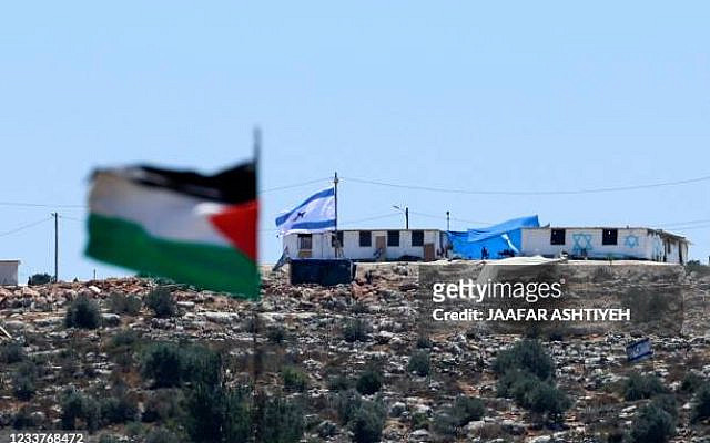 A Palestinian flag flutters on a hilltop in the town of Beita, near Nablus city in the occupied West Bank, on July 2, 2021, amid ongoing rallies in the Palestinian village protesting the newly-established settler outpost of Eviatar (background) on a nearby hill. - Israeli settlers were leaving the wildcat outpost in adherence to an agreement struck with nationalist premier Naftali Bennett's new government, an AFP reporter said. The hilltop area where they have established a settlement lies near Nablus in the northern West Bank, Palestinian territory occupied by Israel since 1967. Under the terms of the deal, those temporary homes will remain, and the Israeli army will establish a presence in the area. (Photo by JAAFAR ASHTIYEH / AFP) (Photo by JAAFAR ASHTIYEH/AFP via Getty Images)