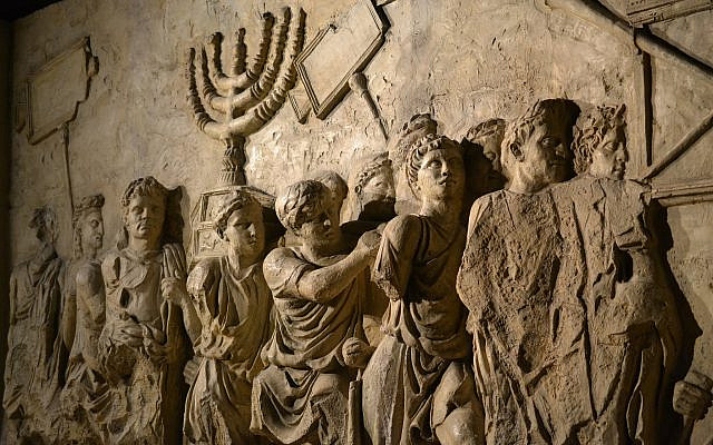 Wall relief on arch of Titus depicting Menorah taken from temple in Jerusalem in 70 AD - Israel history / Shutterstock Library