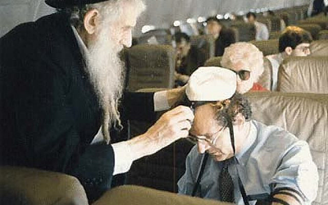 My grandfather, Rabbi Shmuel David Raichik helps a fellow traveler lay Teffilin. (Family Archive)