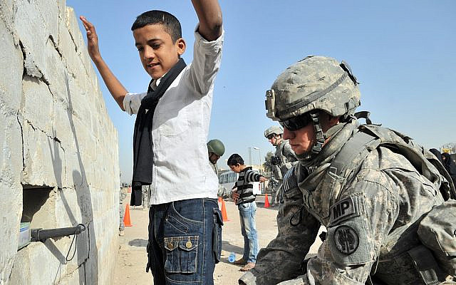 A US soldier searches an Iraqi boy, Basra, Iraq, March 7, 2011. (Public domain photograph from defenseimagery.mil)