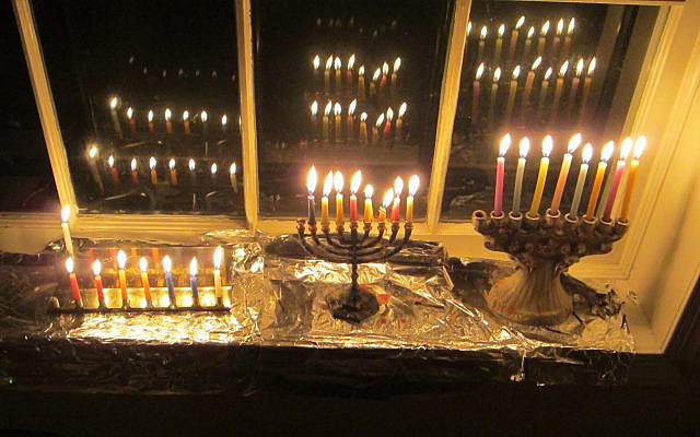 Lit Hanukkah candles reflected in a window