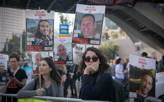 People hold photographs of Israelis held hostage by Hamas terrorists in Gaza, as they attend a protest calling for the government to find a solution to have the hostages released, outside Military Defense Headquarters in Tel Aviv, December 19, 2023. (Miriam Alster/Flash90)