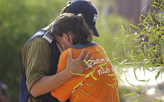 An IDF soldier comforts an evacuee during the evacuation of Neve Deqalim, 2005. IDF archives.