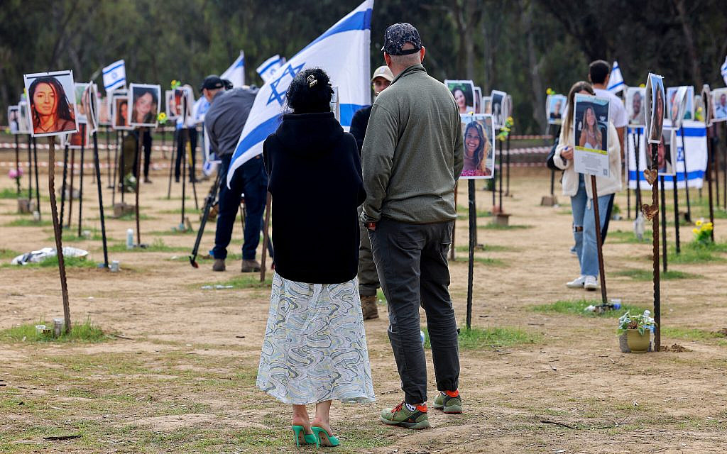 Relatives and friends walk among portraits of people taken captive or killed by Hamas during the Nova music festival on October 7, 2023, during a visit at the site near Kibbutz Re'im in southern Israel, on January 5, 2024. (Jack Guez/AFP)