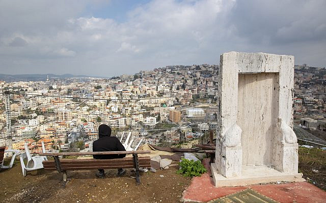 An Arab Israeli youth sits at a view point overlooking the town of Umm al-Fahm, on February 4, 2020. (AP Photo/Oded Balilty, File)