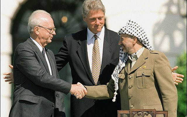 Israeli Prime Minister Yitzhak Rabin (left) and Palestine Liberation Organization Chairman Yasser Arafat (right) shake hands at the White House in front of President Bill Clinton in September 1993. The new play OSLO is a dramatization of events that led to a historic agreement