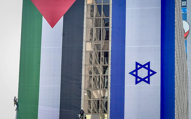 Israeli workers hang large Palestinian and Israeli flags as part of a campaign, in Ramat Gan, June 1, 2022. (Avshalom Sassoni/Flash90)