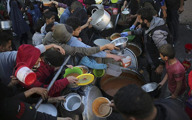 Displaced Palestinians collect food donated by a charity before an iftar meal, on the first day of the Muslim holy fasting month of Ramadan, in the southern Gaza city of Rafah, on March 11, 2024. (AFP)