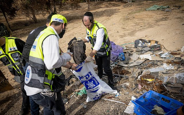 Zaka personnel collect clothes that belong to the victims of the October 7 massacre, near the Israeli-Gaza border, southern Israel, November 19, 2023. (Chaim Goldberg/Flash90)