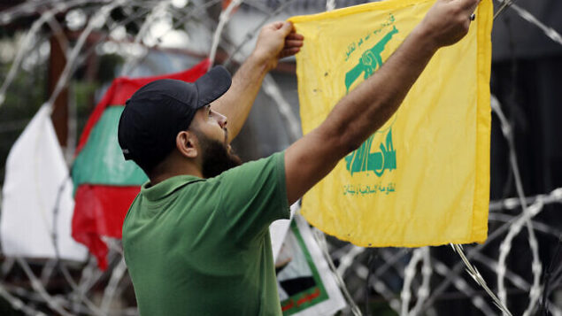 A Hezbollah supporter chants slogans as he holds his group's flag during a protest against U.S. interference in Lebanon's affairs, near the U.S. embassy in Aukar, northeast of Beirut, Lebanon, Friday, July 10, 2020. (AP Photo / Hussein Malla)