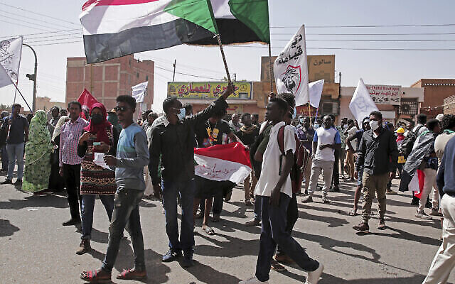 تصویر: مردم پرچم به دست، حین تظاهرات در خارطوم، سودان، ۱۷ ژانویه ۲۰۲۲. هزاران تن از مردم در اعتراض به کودتای ۲۰۲۱ که کشور را به بن بست مرگبار کشانده به خیابان ها ریختند. (AP Photo/Marwan Ali)
