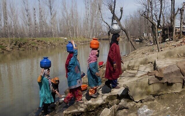 تصویر: در شبی که فردایش روز جهانی آب در «خونیفات» ۳۰ کیلومتری (۱۸ مایل) شمال «سرینگار» ناحیهٔ تحت کنترل هند در کشمیر است، زنان روستا آب آلوده ای که با کوزه های پلاستیکی و مسی از رودخانه کشیده اند، روی سر به خانه می برند؛ ۲۱ مارس ۲۰۱۵. (AP Photo/Dar Yasin/File)