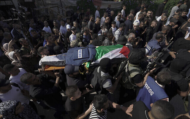 تصویر: شبه نظامی های فلسطینی حین حمل جسد «شیرین ابوعاقله»، روزنامه نگار همکار شبکهٔ الجزیره به سردخانهٔ بیمارستان شهر جنین، کرانه باختری، ۱۱ مه ۲۰۲۲. (AP Photo/Majdi Mohammed)