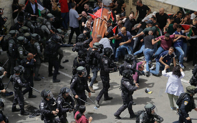 تصویر: پلیس اسرائیل در تشییع جنازهٔ  شیرین ابوعاقله روزنامه نگار الجزیره در اورشلیم، در ۱۳ مه ۲۰۲۲،  با جمعیت عزاداران که تابوت بر دوش می بردند به زدوخورد پرداخت. نزدیک بود تابوت به زمین بیفتد.
(AP Photo/Maya Levin)