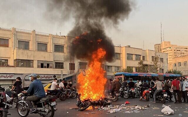 تصویر: عکس فوق که خبرگزاری فرانسه در خارج ایران به دست آورده، جمعیت مردم در تهران، پایتخت ایران را نشان می دهد که در ۸ اکتبر ۲۰۲۲ در اطراف موتورسیکلتی که در آتش می سوزد گرد امده اند. (AFP)